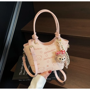 Detail of pink bucket bag featuring cartoon bear prints, textured leather, and plush charm