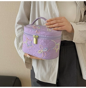 Detail der fliederfarbenen gesteppten Kosmetiktasche mit Sternstickerei und Reißverschluss
