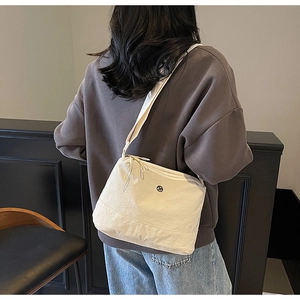 Detailed side view of off-white nylon sling bag with circular logo on a casual model