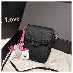 Détail d'un petit sac bandoulière en cuir grainé noir avec pendentif pégase en boîte cadeau