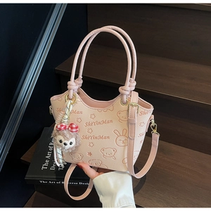 Detail of pink faux leather bucket bag with embossed animal prints and teddy bear charm