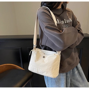 Close-up of lightweight off-white nylon crossbody bag with minimalist adjustable strap