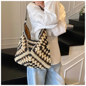 Detail view of handmade woven beach bag with geometric patterns and black shoulder strap