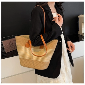 Detail of hand-woven straw tote with leather handles and gradient striped texture