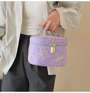 Nahaufnahme der lila gesteppten Kosmetiktasche mit bunten Stern- und Blumenstickereien