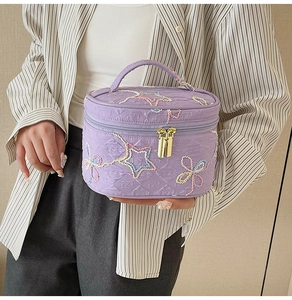 Detail der lila gesteppten Kosmetiktasche mit bunter Stern- und Blumenbestickung