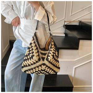 Close-up of contrast woven checkerboard tote bag with black leather straps worn by a model