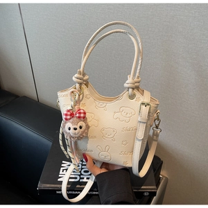 Detail of white PU leather bucket bag with embossed cartoon animals and bear charm