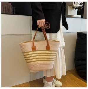 Detail of pink and khaki striped straw tote bag featuring brown leather handles and textures