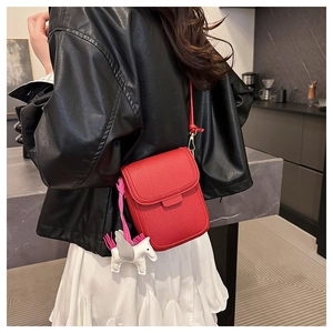 Petit sac bandoulière rouge en cuir grainé avec breloque pégase sur tenue décontractée
