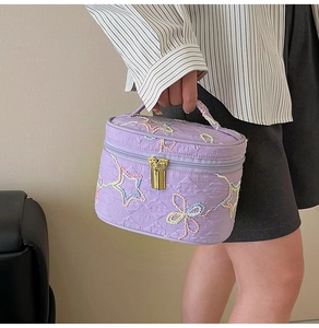 Detailaufnahme der lila Kosmetiktasche aus Kunstleder mit Stickerei und goldenem Verschluss