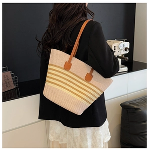 Detail of pink and yellow striped straw tote bag with brown leather shoulder straps