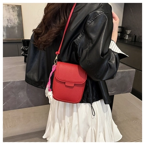 Vue arrière du sac de téléphone rouge en cuir grainé avec charme de cheval sur manteau