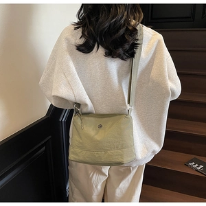 Detail of sage green nylon crossbody bag with adjustable wide strap and metal logo