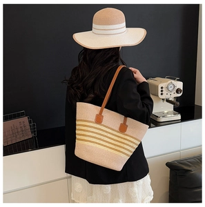 Detailed view of striped straw tote bag and matching sun hat with brown leather handles