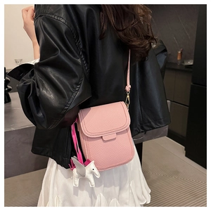 Détail du sac de téléphone rose avec texture litchi et charmant pendentif poney blanc