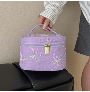 Detaillierte Stickerei von bunten Sternen und Schleifen auf lila Kosmetiktasche