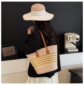 Detail of pink and yellow striped straw tote bag and matching sun hat set for summer