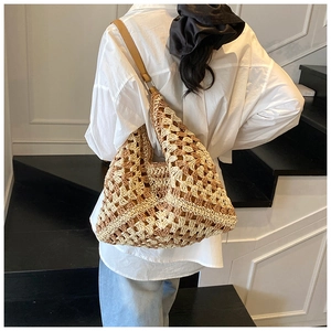 Detail of woven straw tote bag with brown leather strap worn over a white shirt