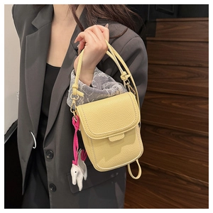 Détail d'un mini sac bandoulière jaune en cuir grainé avec pendentif éléphant