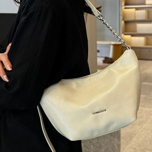 Chic cream leather hobo bag with silver chain strap shown on model's shoulder