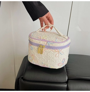 Detail der Stepptextur mit floraler Stickerei und lila Reißverschluss an der Kulturtasche