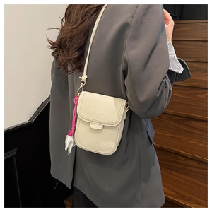 Petit sac bandoulière aspect cuir grainé avec breloque animale porté par un mannequin
