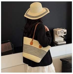 Detail of straw tote bag with black stripes and matching hat in a modern interior setting