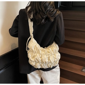 Detail of cream pleated cloud bag showing soft texture on a shoulder strap model