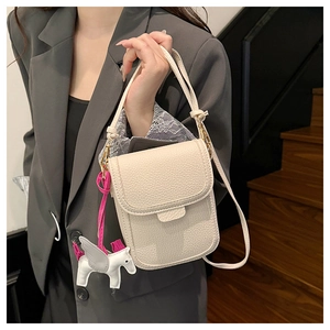 Détail d'un petit sac bandoulière blanc crème avec un pendentif pégase mignon