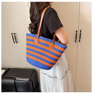 Detail of woven tote bag with blue and orange stripes and brown leather handles