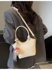 Vintage cream bucket bag with embossed cartoon patterns and plush charm on model