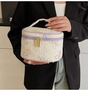 Detailansicht der weißen gesteppten Kulturtasche mit Schmetterlingsstickerei und lila Rand