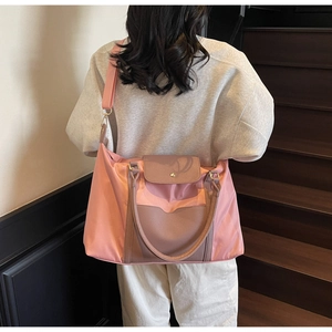Détail du sac cabas en nylon rose avec rabat en cuir marron et large bandoulière réglable