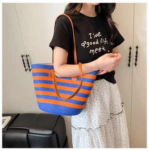 Close-up of blue and orange striped straw tote bag with brown leather straps