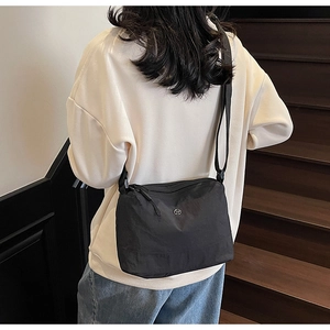 Rear view of a model wearing a black casual canvas crossbody bag on a modern staircase