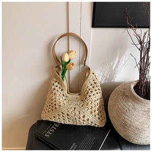 Close-up of hand-woven straw beach bag with hollow-out patterns and brown leather handle