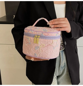 Nahaufnahme der rosa gesteppten Kosmetiktasche mit Sternenstickerei und lila Zippern