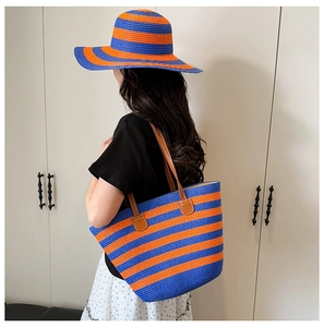 Detail of blue and orange striped straw tote bag and wide-brim hat set for summer
