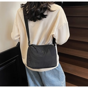 Detail view of a black crescent canvas crossbody bag with adjustable strap and logo