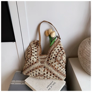 Detail of a hand-woven straw beach bag with brown faux leather strap on a suitcase