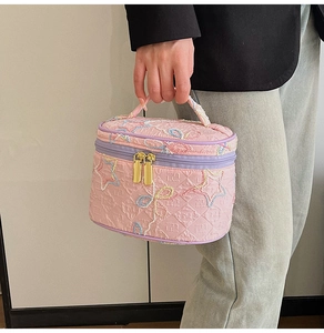 Detail der rosa gesteppten Kosmetiktasche mit farbiger Sternstickerei und Goldreißverschluss