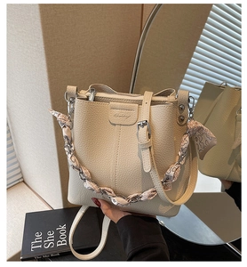 Detail of cream bucket bag featuring leopard silk scarf chain and grainy leather texture