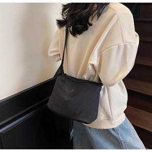 Side view of a model wearing a black minimalist canvas crossbody bag on a stairwell