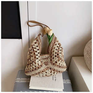 Detail of hollow crochet woven straw beach bag with brown leather shoulder strap