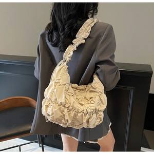Detail of beige pleated cloud bag shown on shoulder with stylish texture and ruching