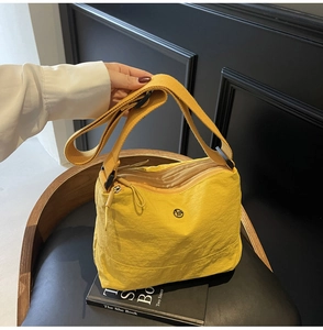 Detail of yellow nylon crossbody bag with multi-zipper compartments and wide strap