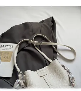 Close-up of white lychee leather bucket bag with printed heart silk scarf on suit jacket