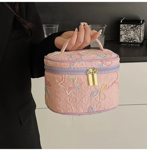 Detail der rosa gesteppten Kosmetiktasche mit Sternstickerei und Goldreißverschluss