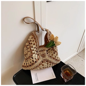 Close-up of handmade crochet shoulder bag with contrast stitching and leather strap detail